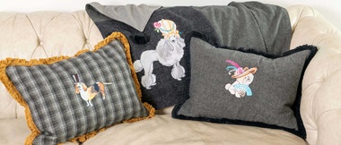 Gestickte Hunde auf Kissen und Überwurf auf beigem Sofa