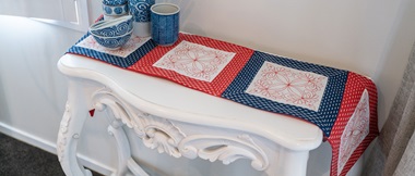 chemin de table bleu et rouge fait de carrés sur une table d'appoint