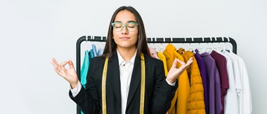 Woman with sewing tape meditates in front of clothes