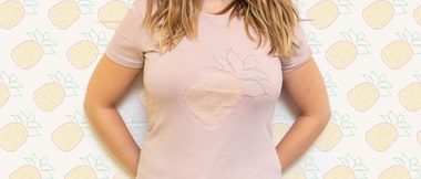 Femme portant un t-shirt rose avec ananas brodé sur le devant