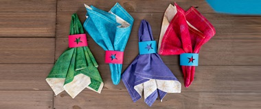four cloth napkins in differnt coulours on wooden background