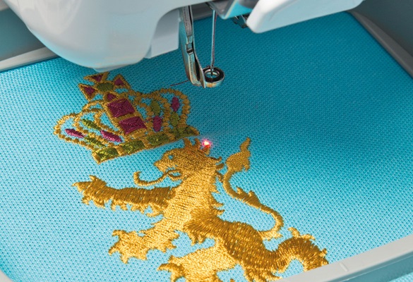 Roter LED-Pointer auf goldenes Löwen-Stickmuster auf blauem Stoff