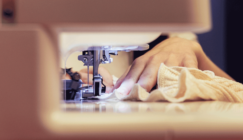 Mains guidant le tissu à travers la surjeteuse Airflow 3000