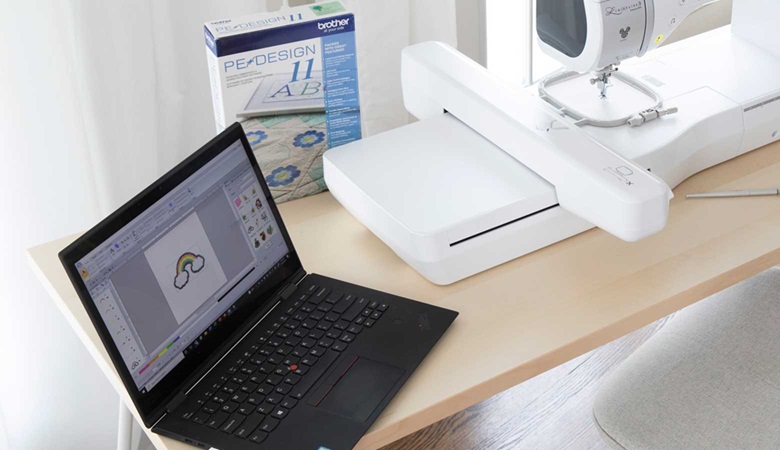 Laptop met PE-design naast Naaimachine op tafel