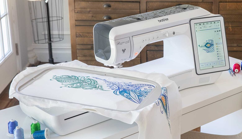 Große blaue Stickerei im Rahmen neben Stickmaschine
