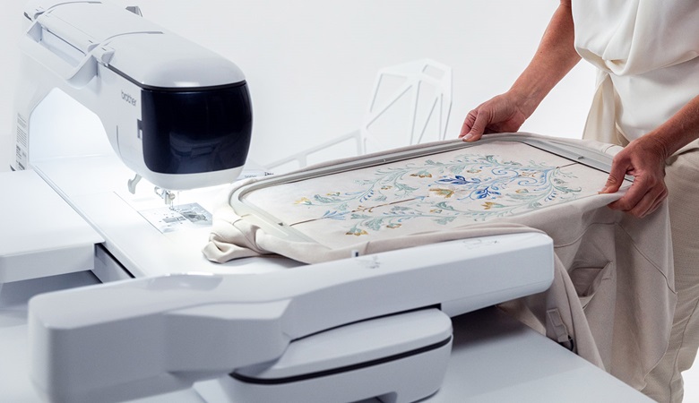 Brother Aveneer EV1 on white table with large embroidery in frame