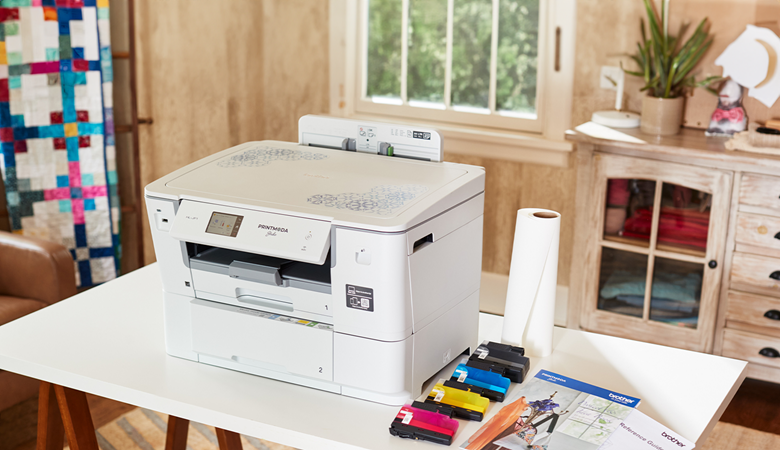 PrintModa Studio Stoffdrucker auf dem weißen Tisch mit 4 Tintenpatronen an der Seite.