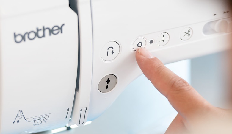 finger pushing lockstitch button on Brother A-series sewing machine