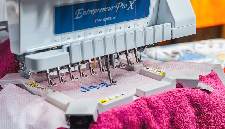 Brother embroidery machine stitching name on fabric.