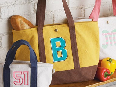 Gelbe und weiße Taschen mit gestickten Buchstaben und Zahlen