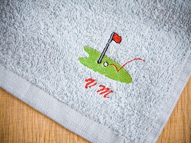 Blauwe golfhanddoek met geborduurd golfterrein