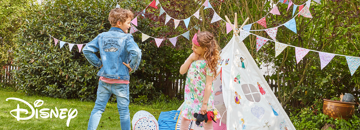 Zwei Kinder vor Zelt mit gestickten Disney-Motiv in Garten